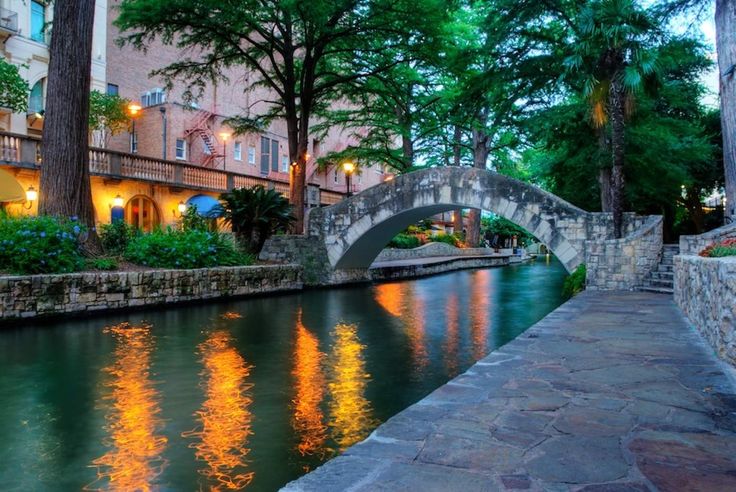 a stone bridge over a river next to tall buildings