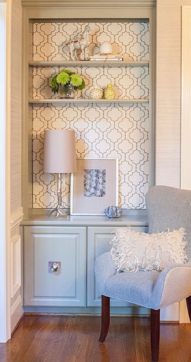 a white chair sitting in front of a wall mounted shelf with vases and flowers on it