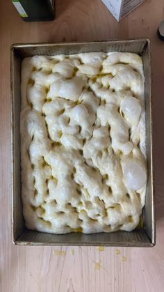 a pan filled with dough sitting on top of a wooden table next to a box