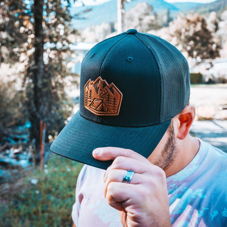 a man wearing a green hat with a brown patch on the front and back of it