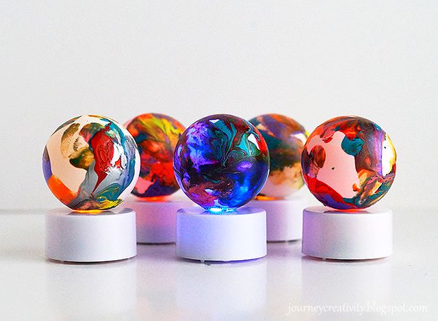 four colorful marbles are on white bases