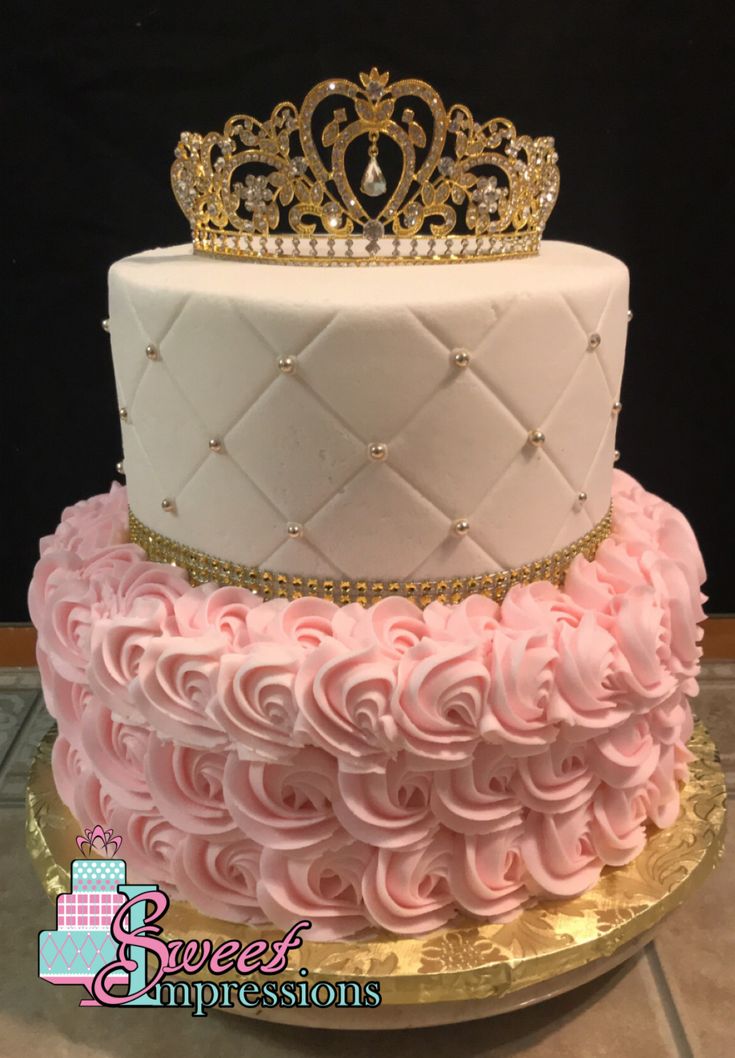 a three tiered cake with pink frosting and a gold crown on top