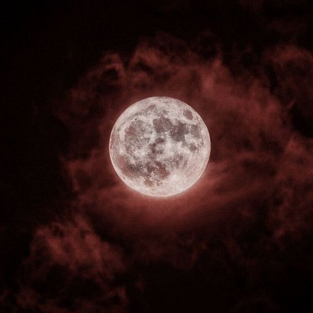 the full moon is seen through some clouds