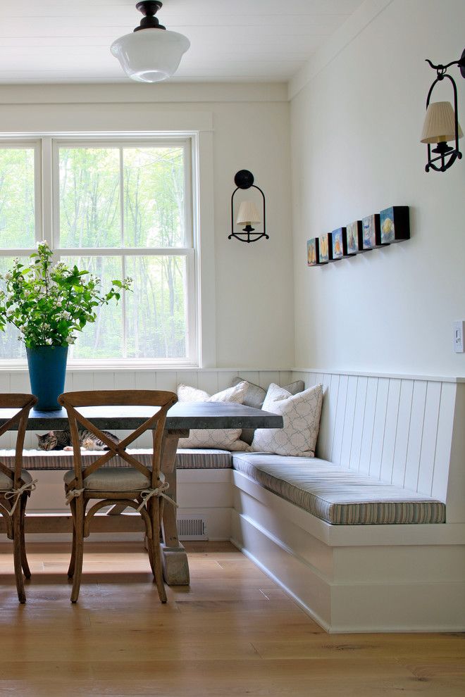 a dining room table with chairs and a bench in front of a window that overlooks the woods