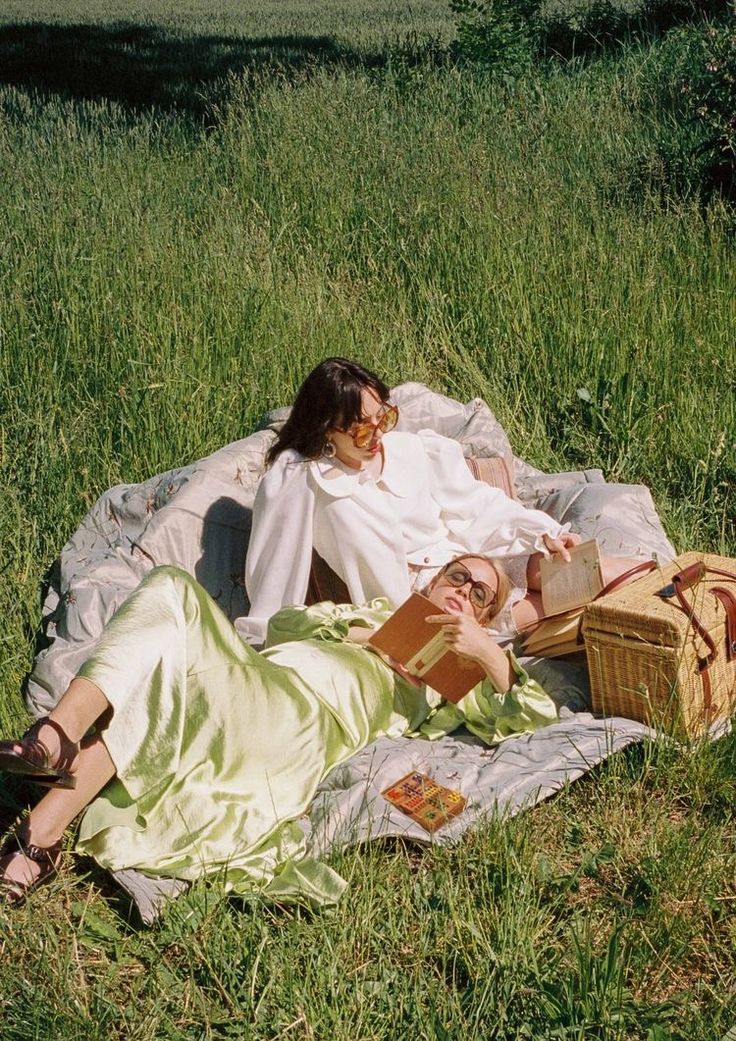 two people laying on a blanket in the grass