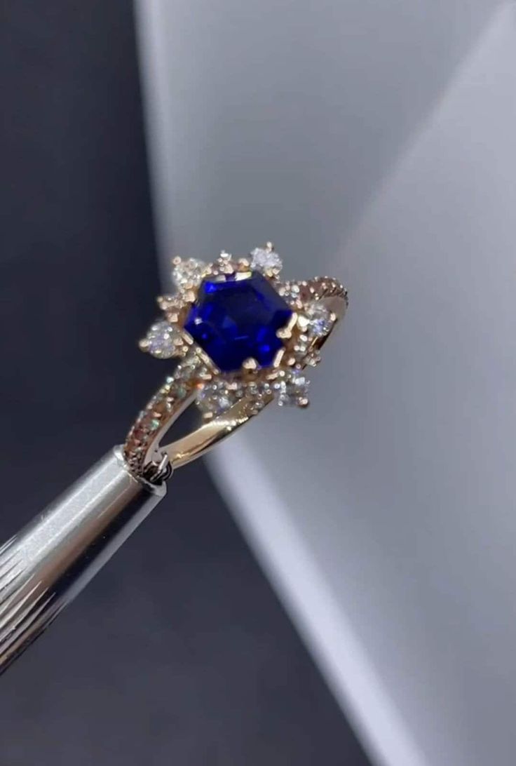 a diamond and blue sapphire ring being held by a person's hand