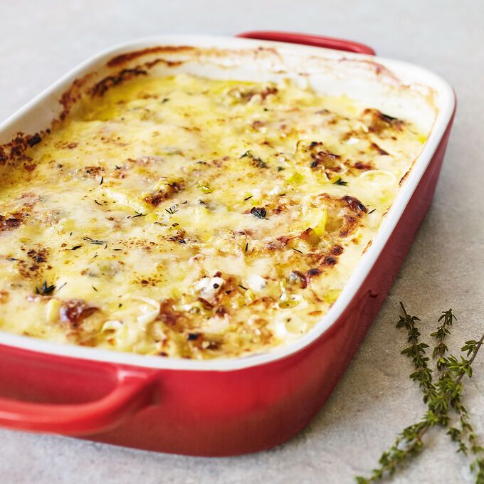 a red casserole dish with cheese and herbs