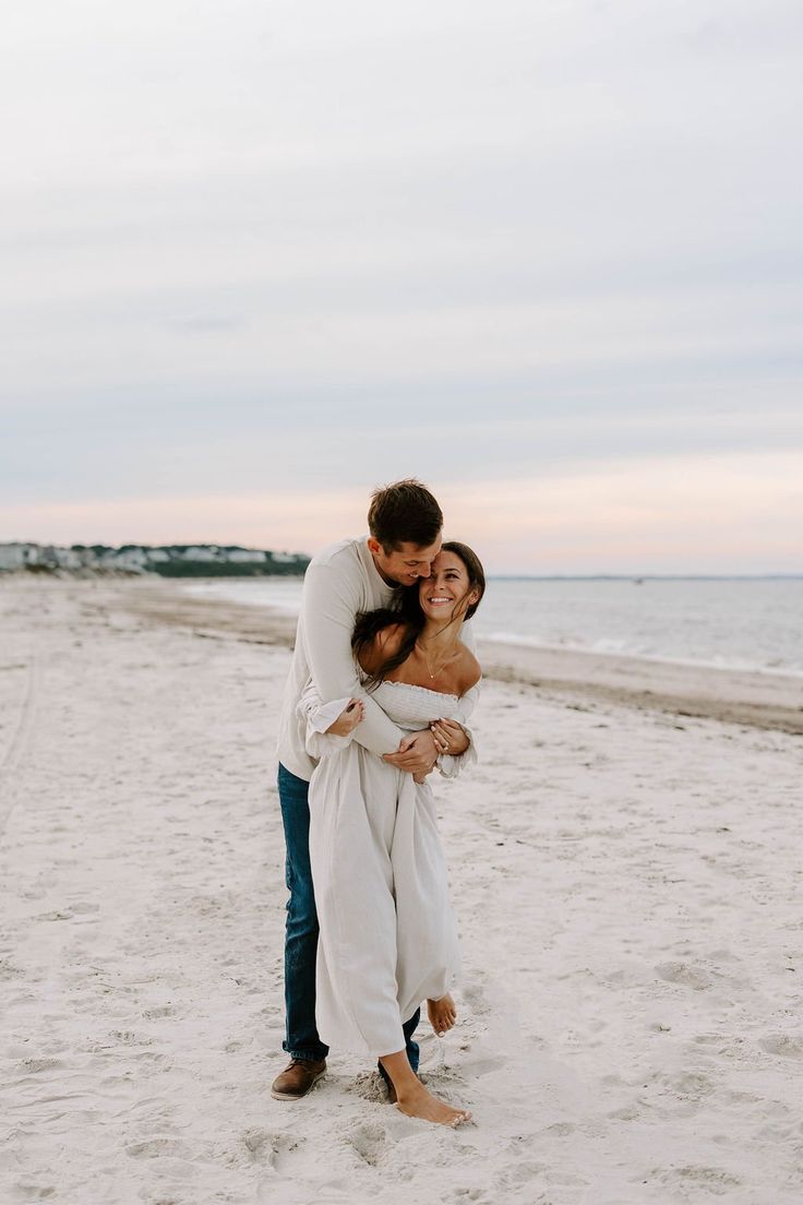 a man and woman hugging on the beach