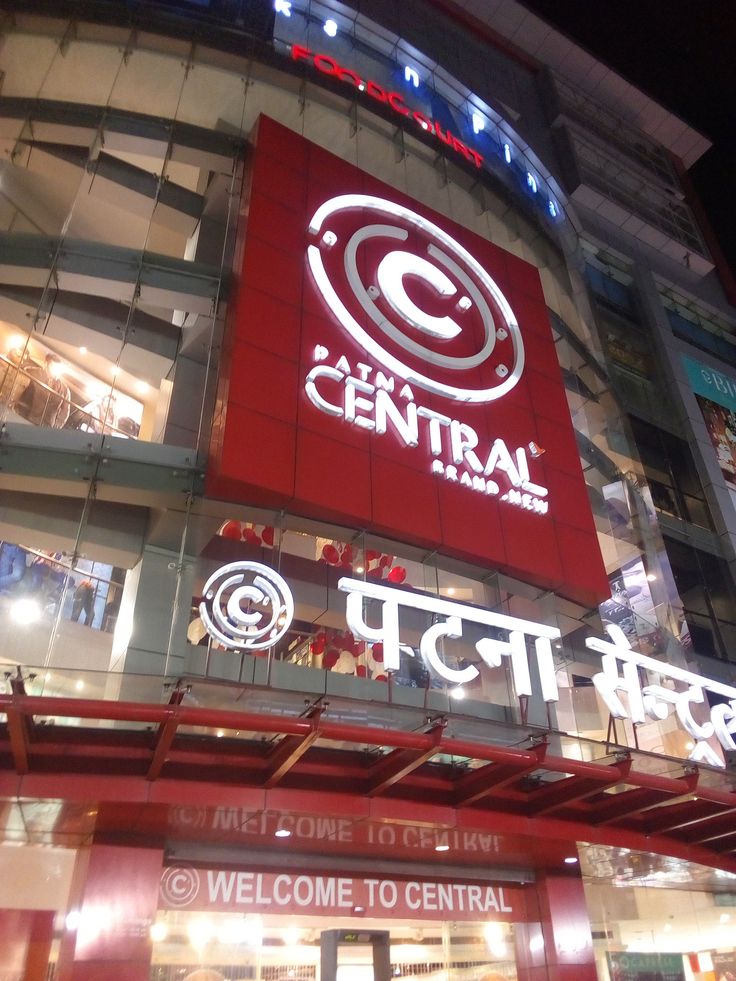 the entrance to central is lit up in red and white at night, with neon signs above it