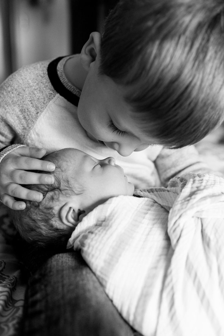 a young boy is holding his newborn baby