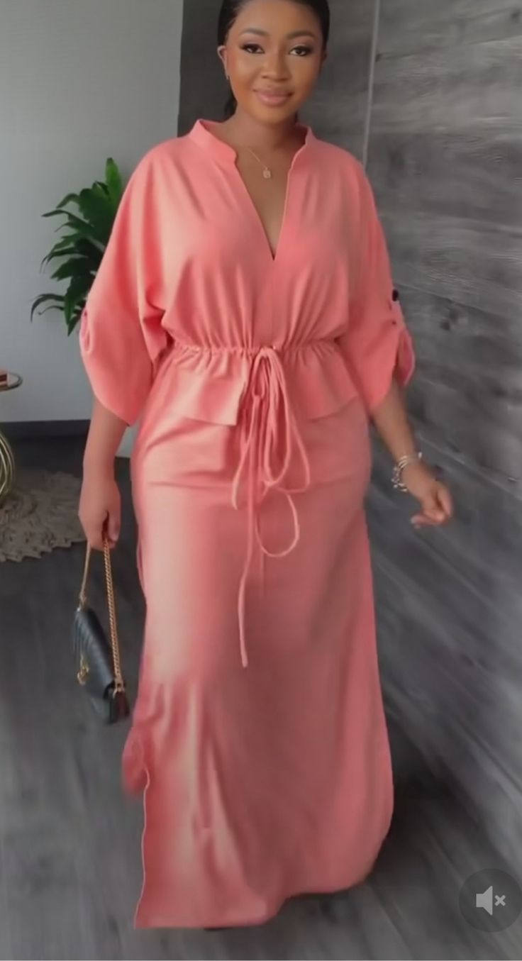 a woman wearing a pink dress and holding a purse