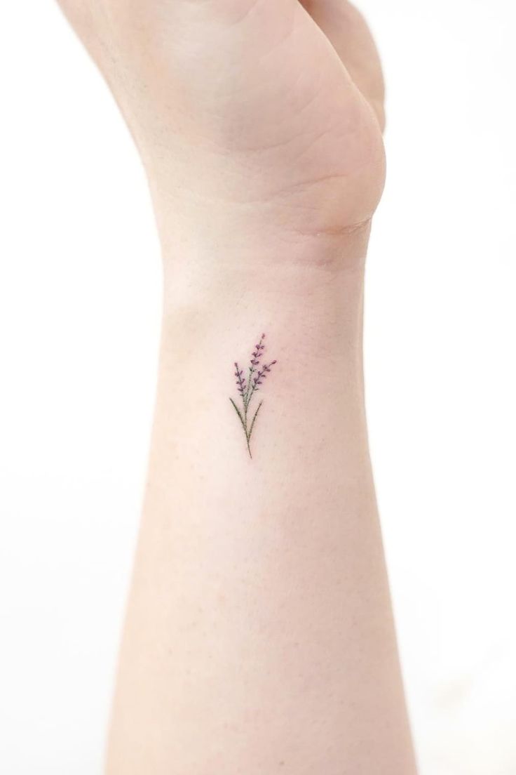 a small lavender flower tattoo on the left side of the wrist is shown in purple