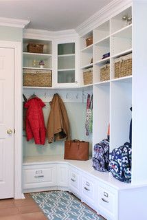 a white closet filled with lots of coats and purses next to a blue rug