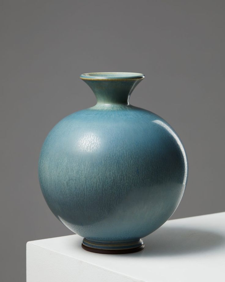 a large blue vase sitting on top of a white table next to a gray wall