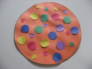 an orange paper plate with colorful polka dots on the top, and one circle has been cut out into smaller circles