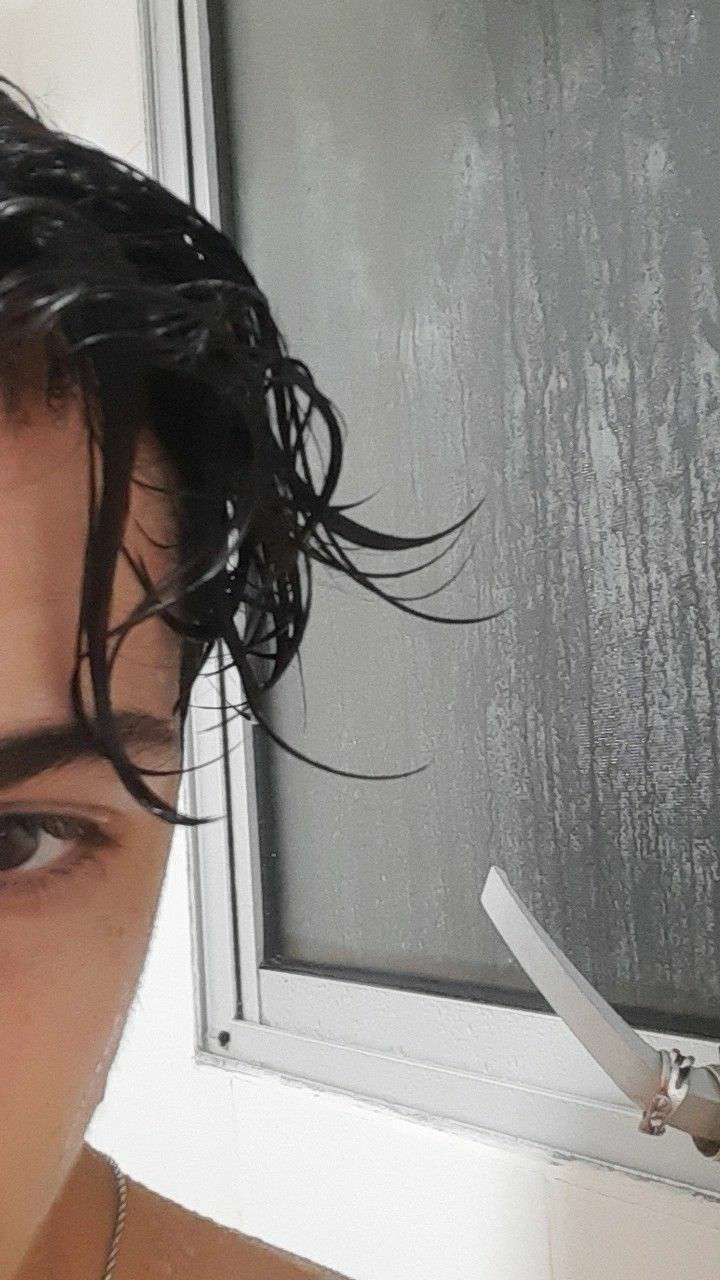 a man with wet hair and scissors in front of a window