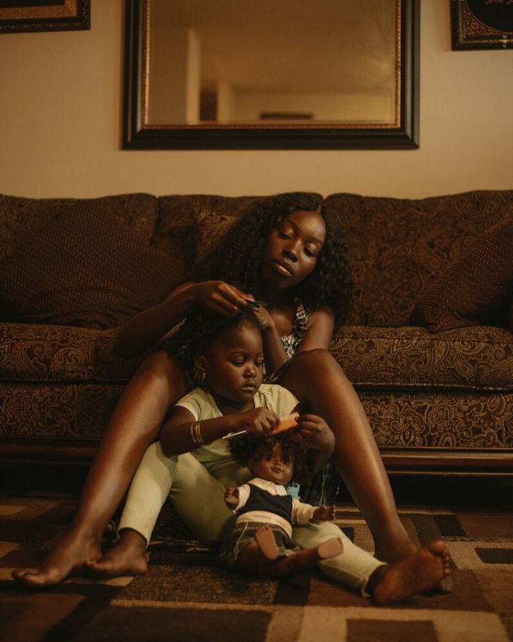 two women are sitting on the floor while one woman combs her daughter's hair