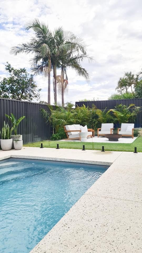 an empty swimming pool with lounge chairs and palm trees in the backround area