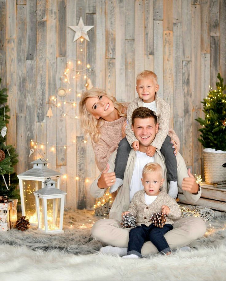 a family posing for a christmas photo in front of a wooden wall with lights and presents