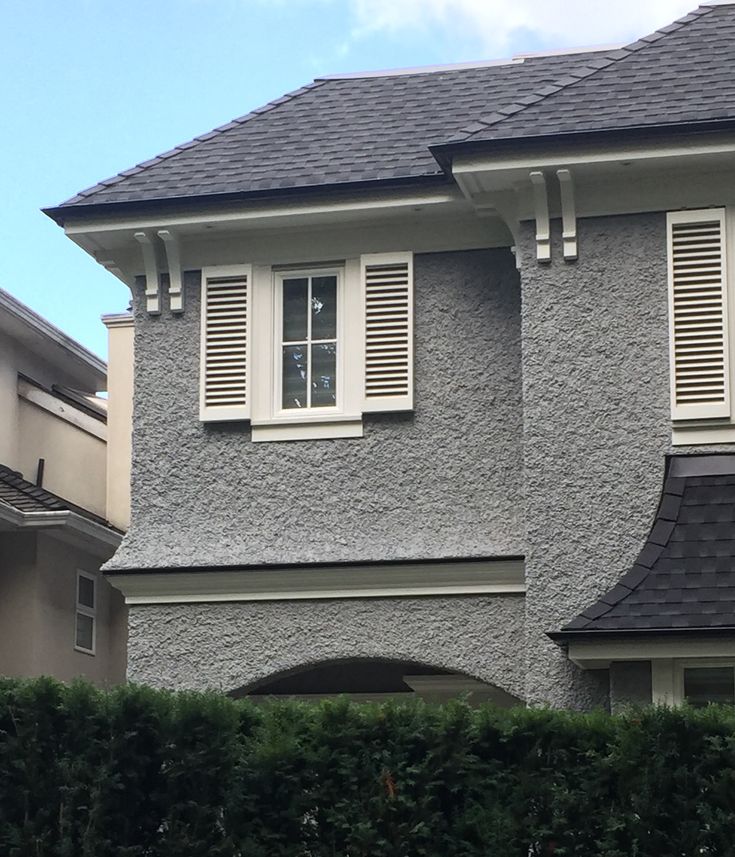 a gray house with white shutters and a clock on the side of the building