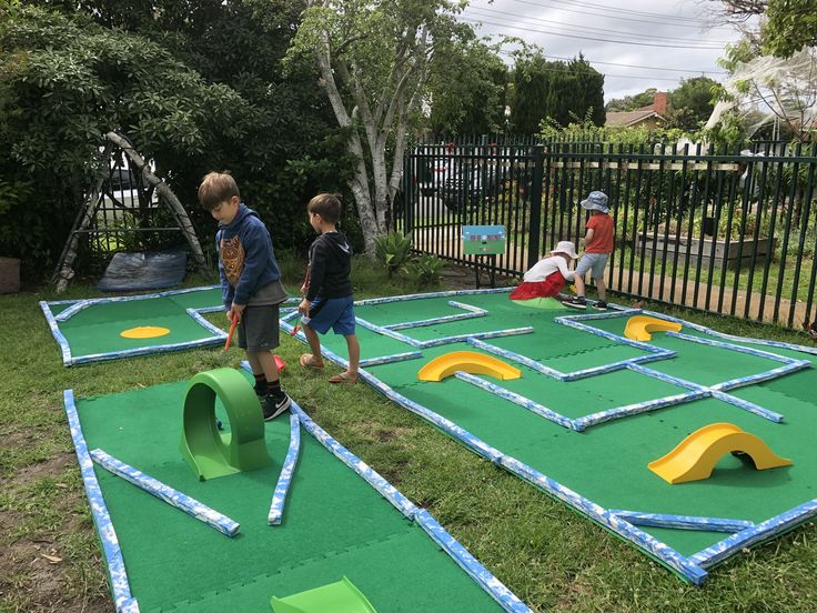 two young boys playing mini golf in the yard