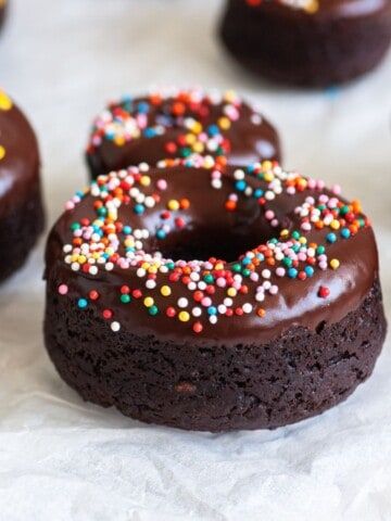 chocolate doughnuts with sprinkles on white paper