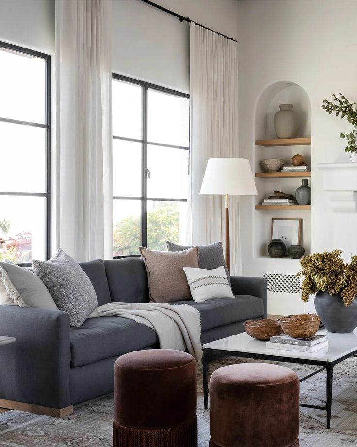 a living room filled with lots of furniture next to a fire place and large windows