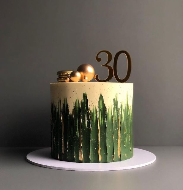 a green and white cake with gold decorations on it's top, sitting on a table