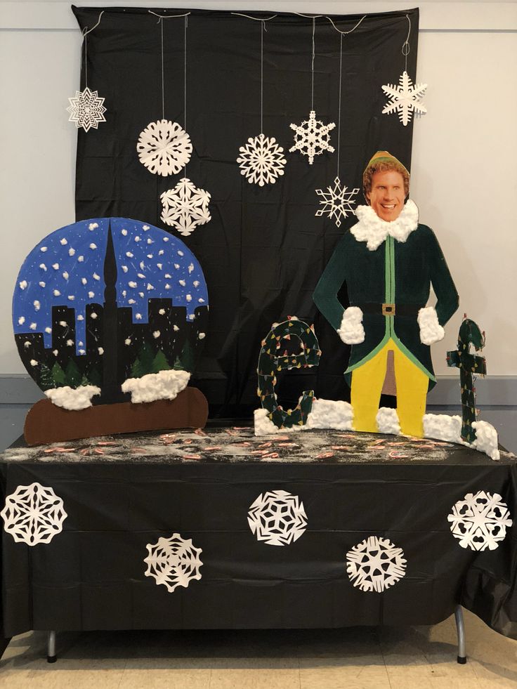 a table topped with snowflakes and paper mache figures in front of a black backdrop