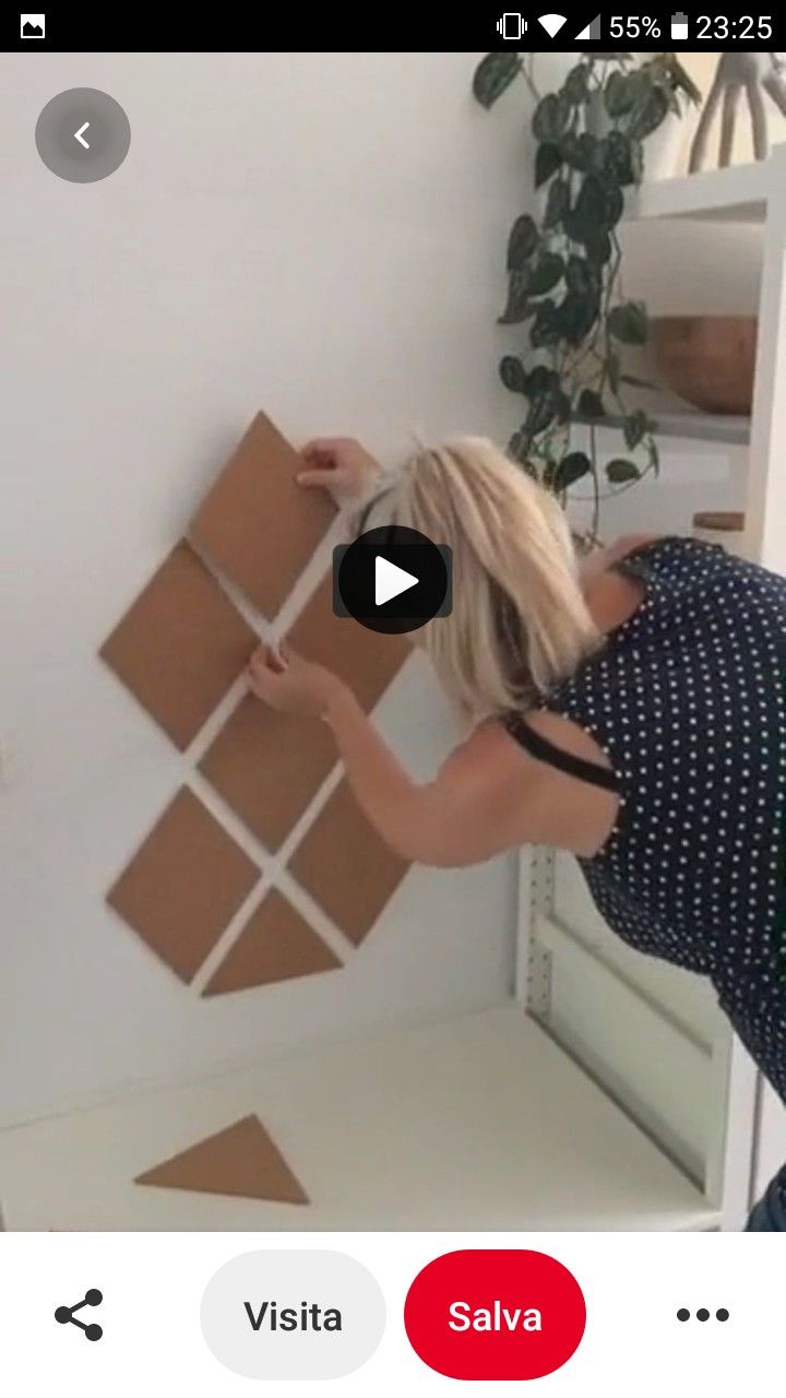 a woman is painting the wall in her living room with brown cardboard squares on it