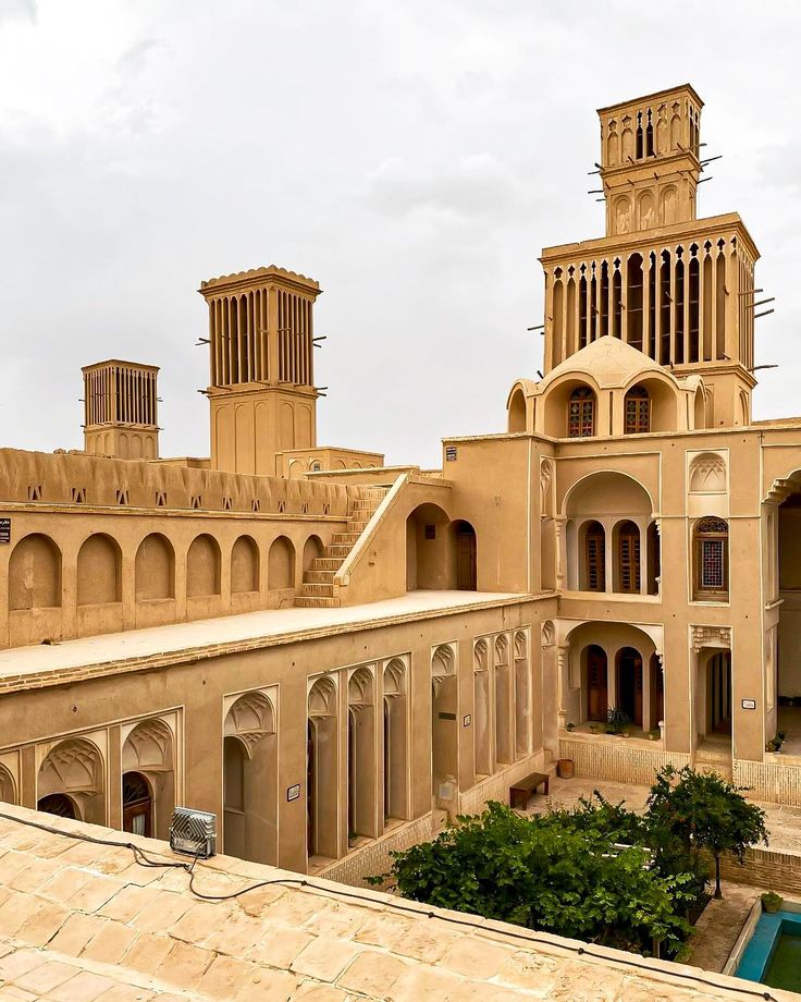 an old building with two towers on each side and a pool in the middle outside