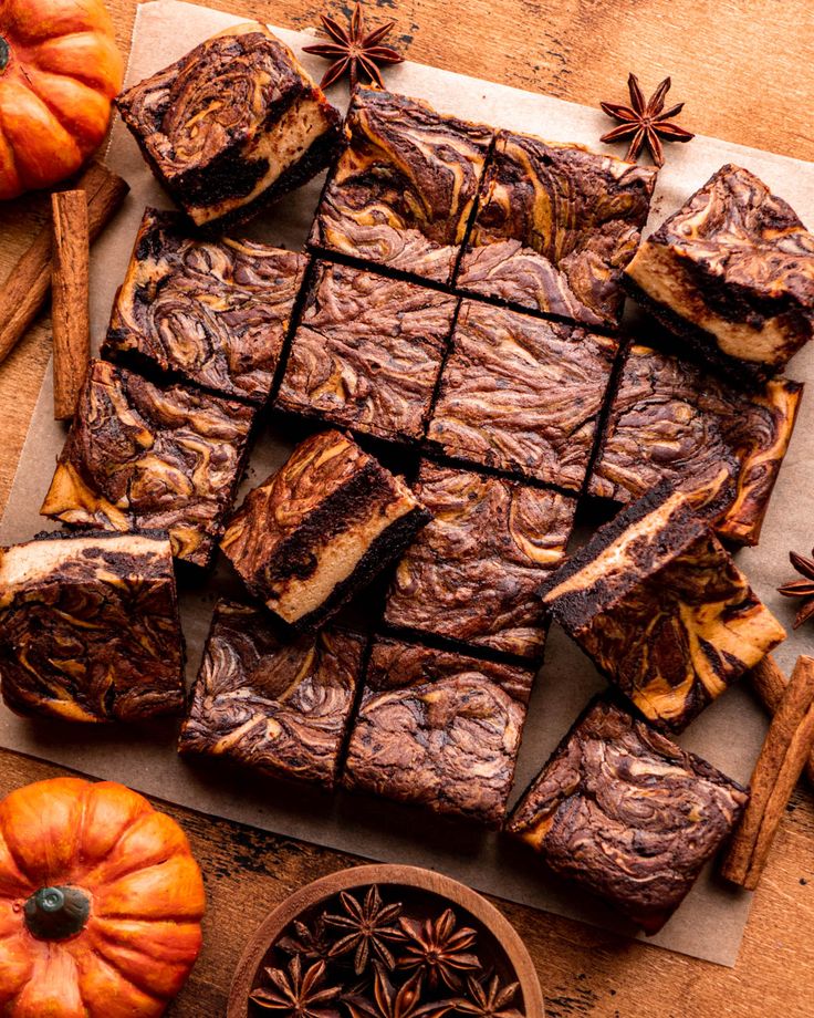 brownies cut into squares on top of a cutting board next to pumpkins and cinnamon sticks