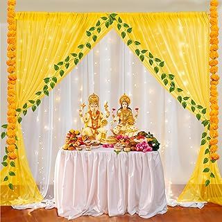 a decorated stage with yellow drapes and white table cloths, two statues sitting on top of each other