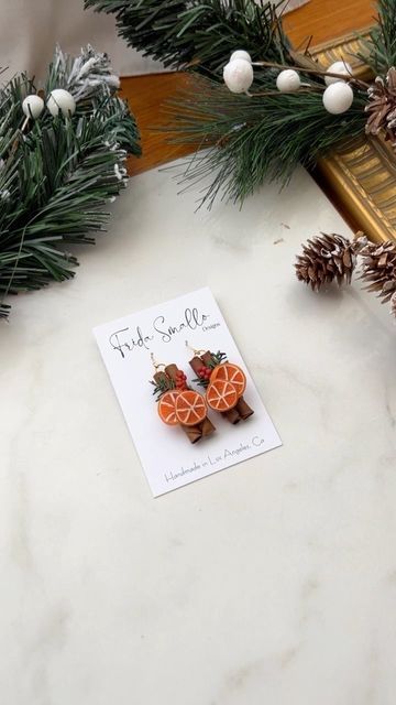 two oranges are sitting on a table next to pine cones and fir branches with the price tag