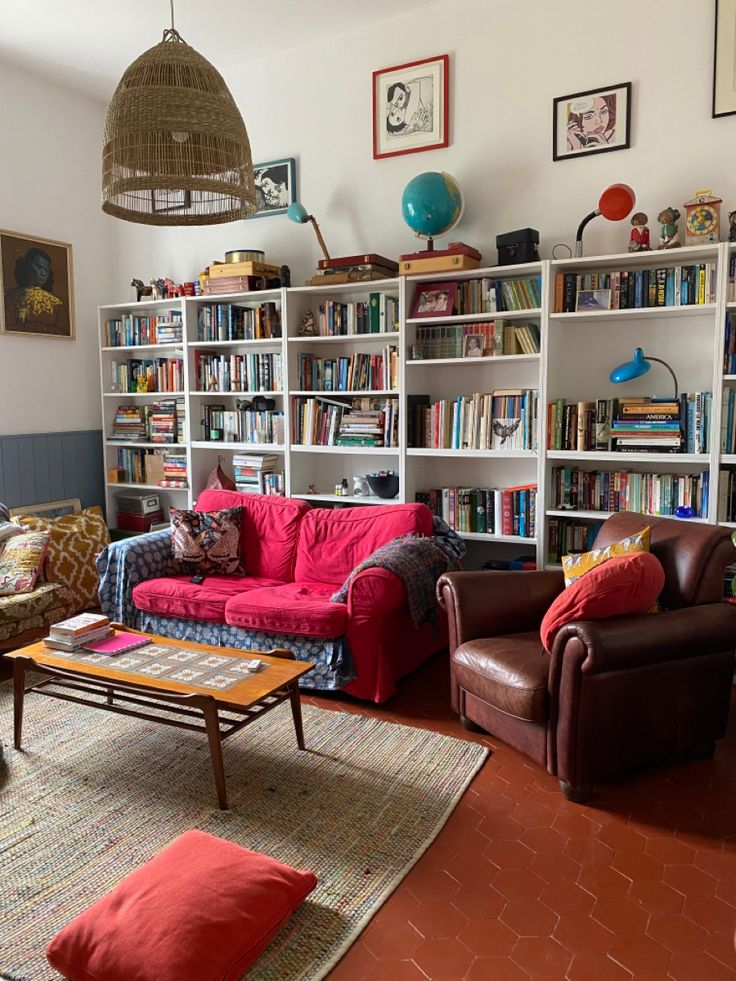 a living room filled with lots of furniture and bookshelves full of books on top of them