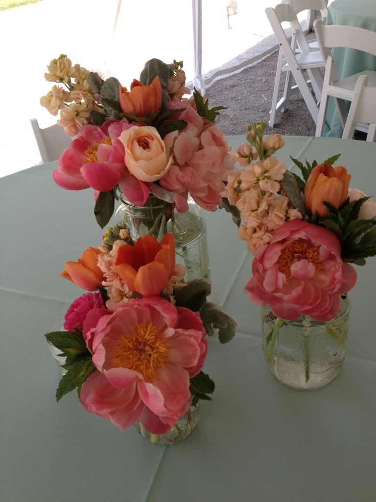 two vases filled with flowers sitting on top of a white tablecloth covered table