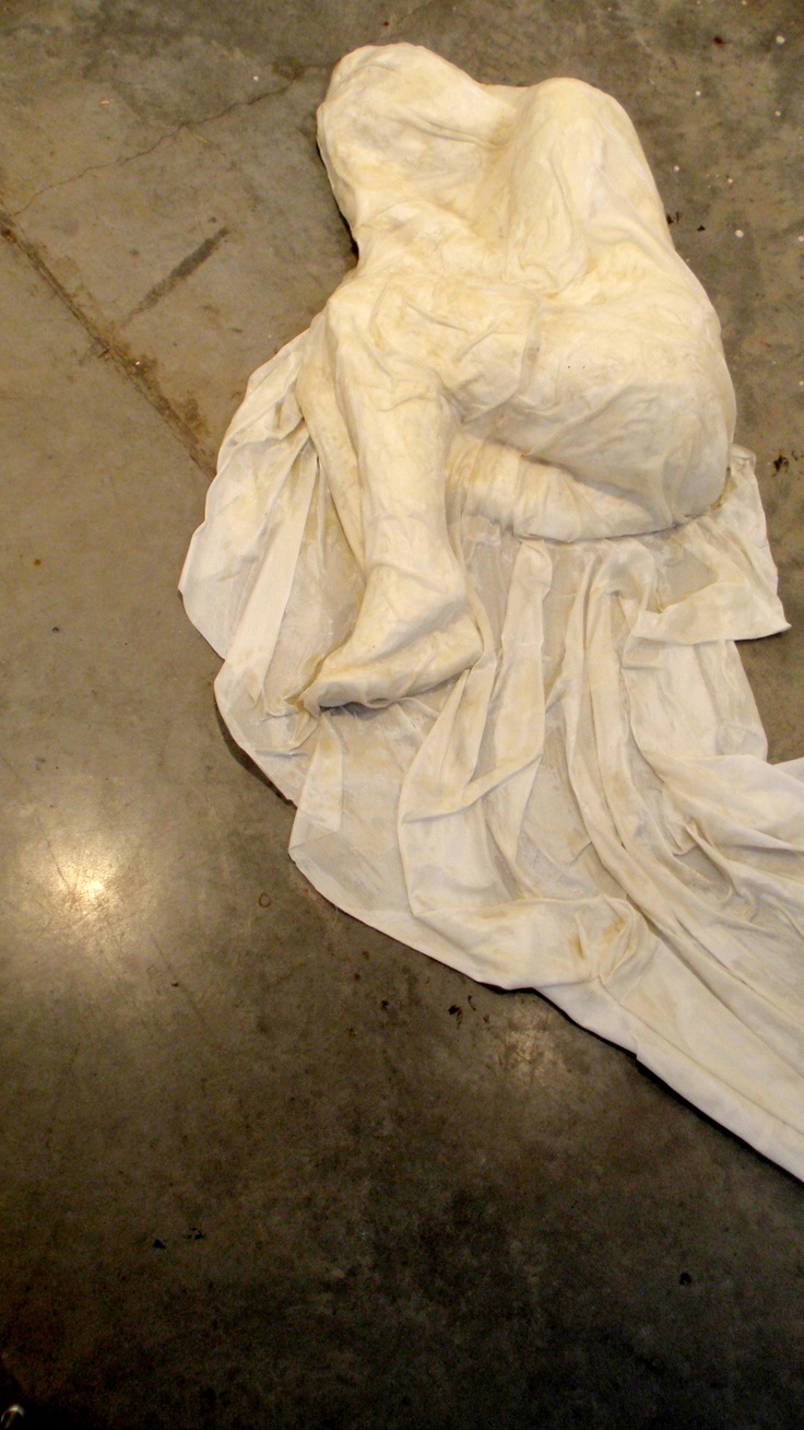 a pile of white cloth sitting on top of a cement floor next to a fire hydrant