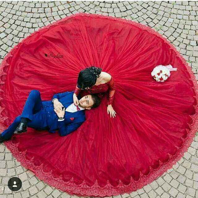 a man and woman laying on top of a large red object in the middle of a cobblestone floor