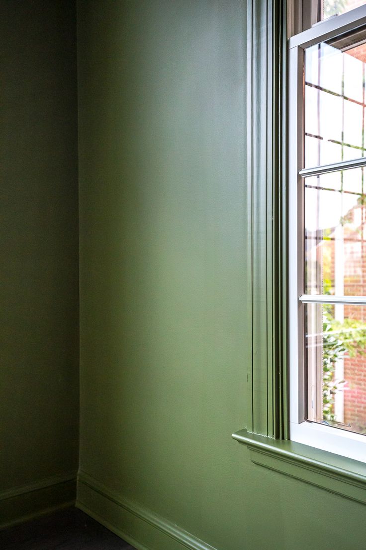 the corner of a room with a window and green walls, painted in light green