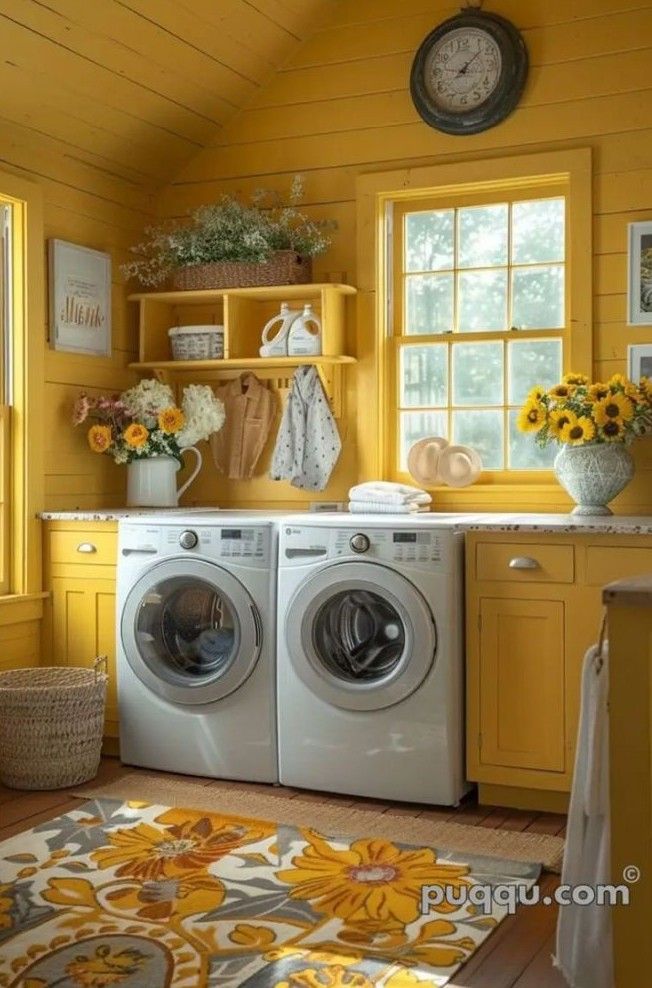 a washer and dryer in a small room with yellow walls, sunflowers on the window sill