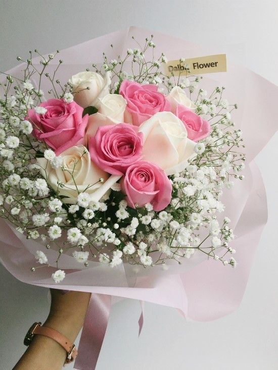 a bouquet of pink and white roses in someone's hand