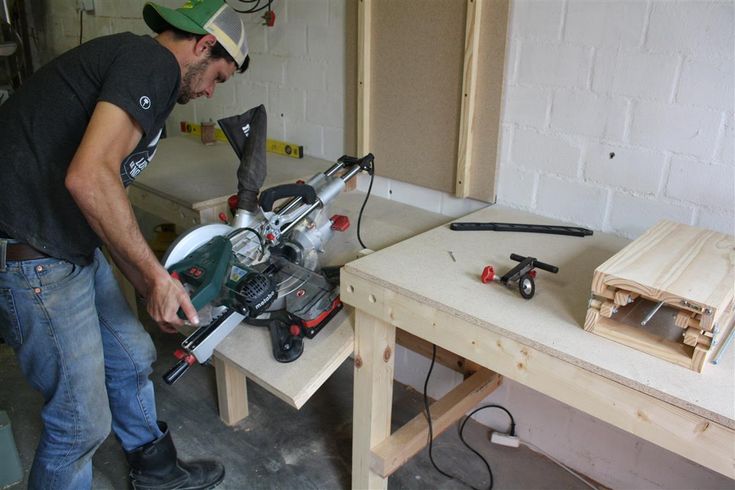 a man using a circular saw to cut wood on a workbench in a workshop