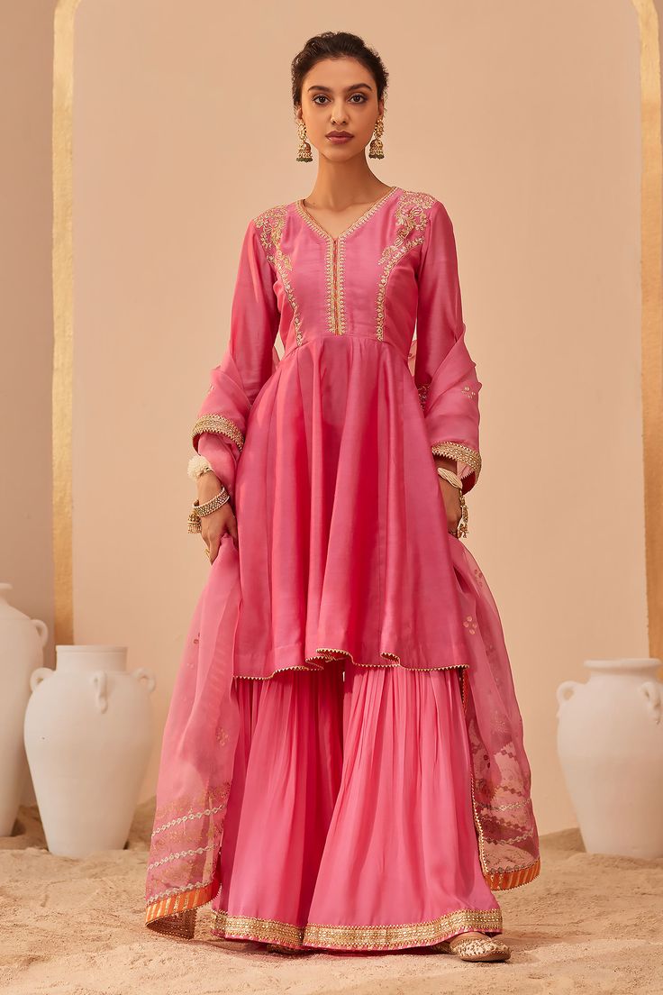 Flamingo pink peplum anarkali with tilla, patra, zari thread embroidery. Paired with gharara and geometric hand block print dupatta. Components: 3 Pattern: Embroidery Type Of Work: Tilla, patra, zari thread Neckline: V neck Sleeve Type: Three quarter Fabric: Kurta: Silk Chanderi, Gharara: Georgette, Dupatta: Silk Organza Color: Pink Other Details:  Tiered gharara Gota lace embroidered hem Sheer printed dupatta Occasion: Sangeet - Aza Fashions Pink Gharara, Gharara Pants, Velvet Kurta, Blouse Yoke, Set Saree, Flamingo Pink, Sharara Set, Organza Dupatta, Indian Fashion Designers