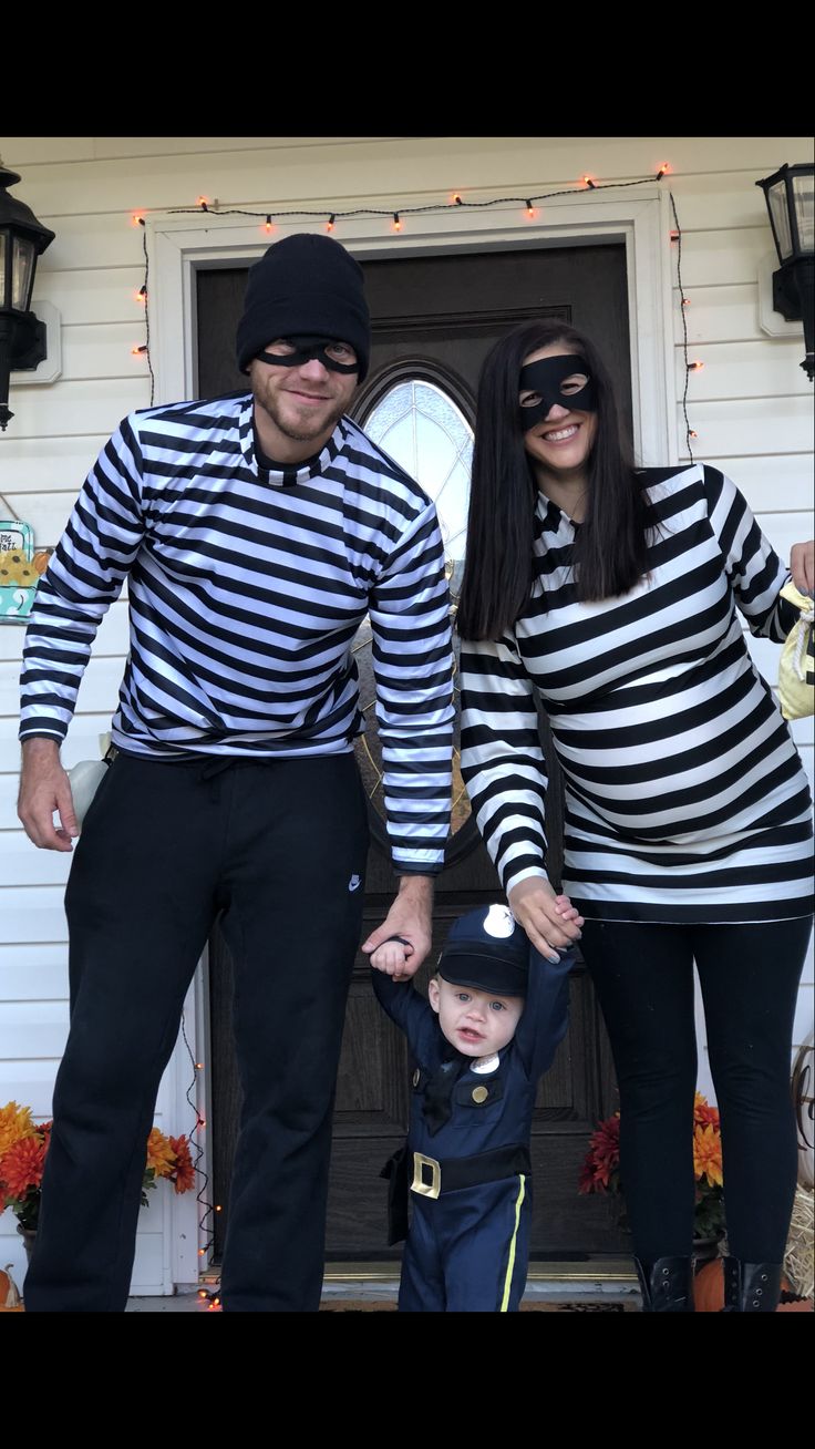 a man and woman in striped shirts standing next to a small child wearing black glasses