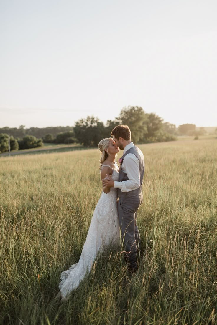 a bride and groom kissing in a field