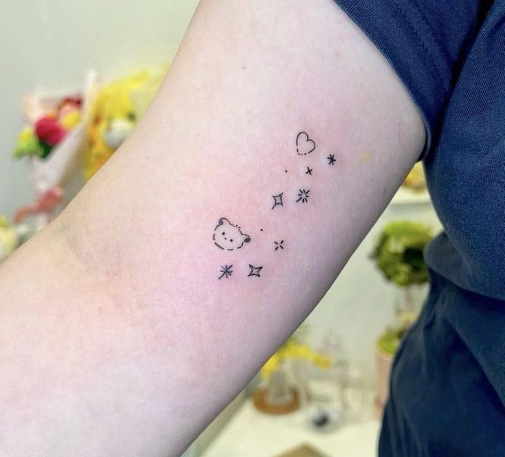 a person with a small tattoo on their arm that has stars and cats in the sky