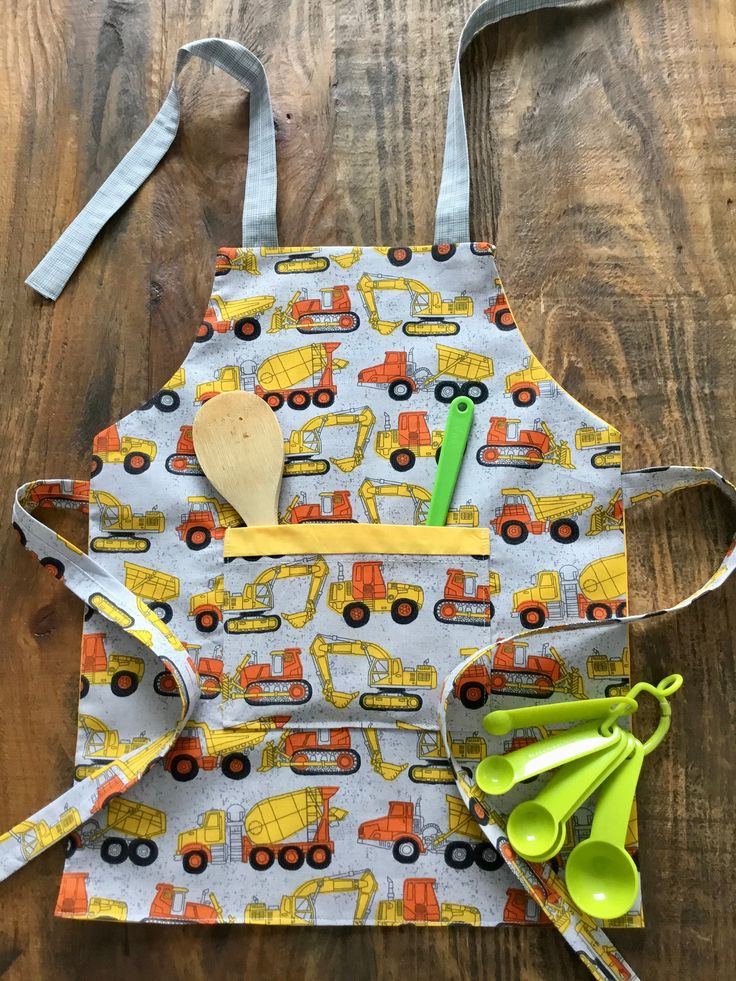 a child's apron with construction vehicles on it and spoons in the pocket