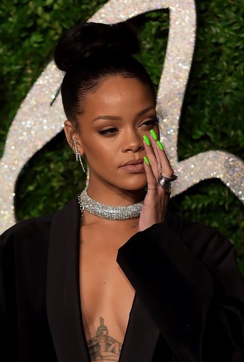 a woman with green nail polish holding her hand up to her face