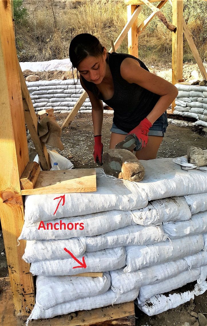 a woman in black shirt and red gloves next to stacks of sandbags with words on them