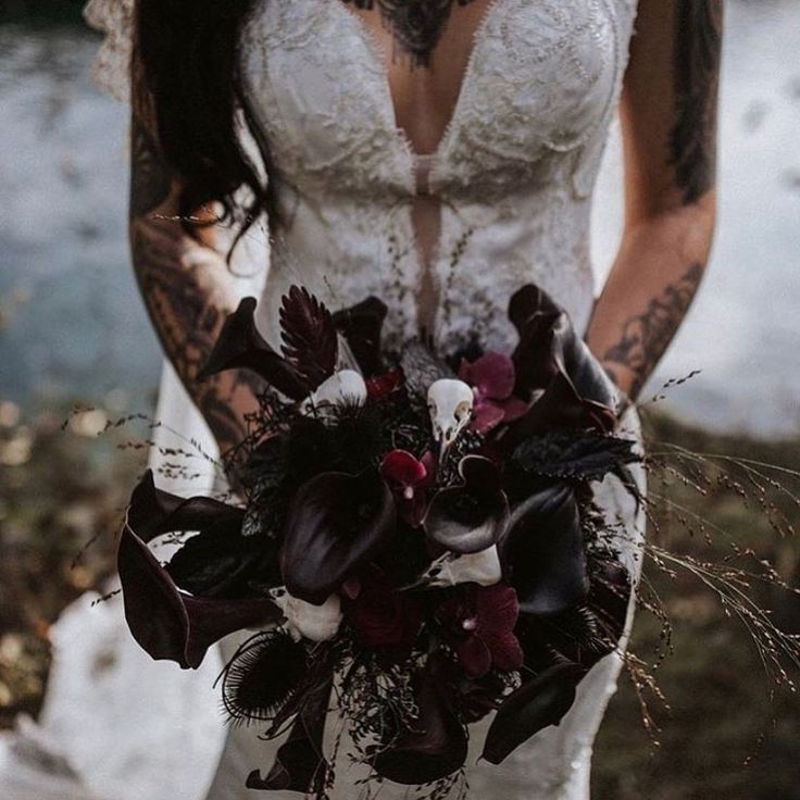 a woman in a wedding dress holding a bouquet with flowers on her chest and arm